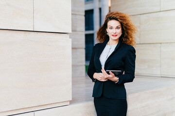 Elegant businesswoman with tablet, luxuriant hair. Gorgeous, tech-savvy, on the way to work.