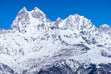 Fototapeta na wymiar Beautiful panoramic view Ushba peak in Caucasus mountains covered with snow in winter and blue sky in Mestia Svaneti Georgia