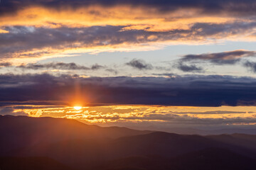 Fototapeta na wymiar Winter Sunset through lines of clouds over Blue Ridge Mountains