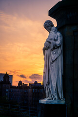 An angel statue in a graveyard at sunset