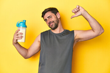 Fit man with protein shake, yellow studio background feels proud and self confident, example to...