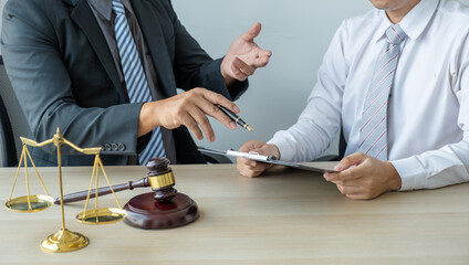 Lawyer hand holding pen and providing legal consult business dispute service at the office with justice scale and gavel hammer