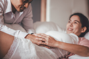 Fototapeta premium Love of family, motherhood, parenthood and expectation concepts. Asian woman and husband caressing his girlfriend belly and feeling the movements of the baby.