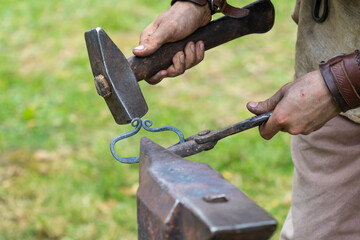 Blacksmith working iron into shape on an Anvil with a hammer.
