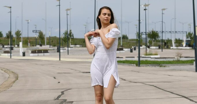 Young beautiful girl in a summer white dress with bare shoulders
