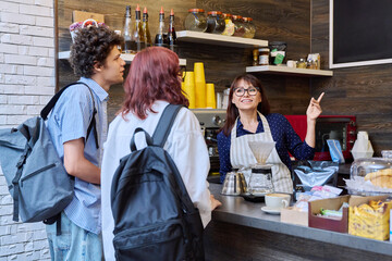 Customers of coffee shop making an order, talking to female barista cafe worker