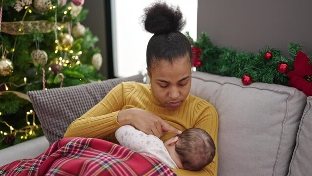Mother and son celebrating christmas breastfeeding baby at home