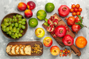 top view fresh red pomegranates with tangerines cake and apples on the light-white desk fruits fresh mellow ripe tree