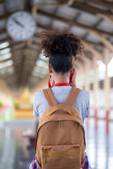 Young Asian African woman traveler with backpack in the railway train, traveler girl walking stand sit waiting take a picture on railway platform