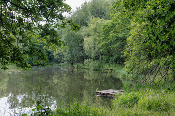 Landscape with a lake and wooden pier in the middle of the forest