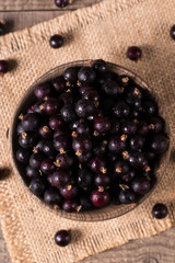 Black currant in a bowl on wooden background. Organic berries. 