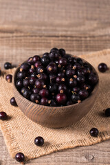 Black currant in a bowl on wooden background. Organic berries. 