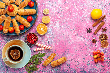 top view sweet delicious bagels inside tray with plums and cup of tea on light-pink desk pastry cake biscuit cookies sweet sugar