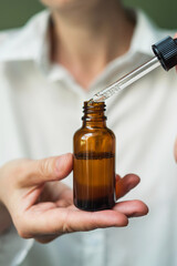 Essential oil with a pipette in the hands of a woman with space to copy. Women's hands with a bottle of oil and a pipette - the sphere of beauty