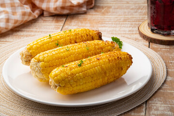 Grilled fresh corn with butter and parsley in white plate