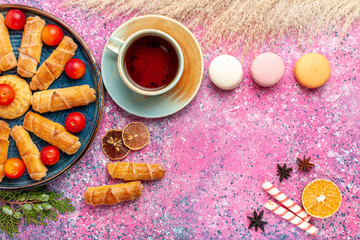 top view sweet delicious bagels with fresh sour plums french macarons and cup of tea on light pink desk cake biscuit cookie sweet sugar pie