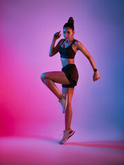 Young Asian sporty woman in sports outfits doing stretching before workout in fitness studio neon background. Healthy young woman warming up.
