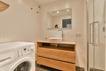 a laundry room with a washer and dryer in the corner, next to a mirror on the wall