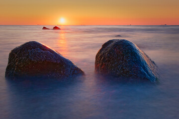 Sonnenuntergang mit Steine im Vordergrund, und einer Langzeitbelichtung