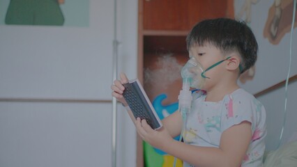 A little boy having a medicine inhalation with a nebulizer mask in the hospital.