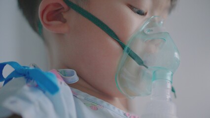 A little boy having a medicine inhalation with a nebulizer mask in the hospital.