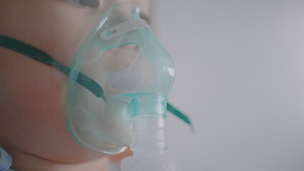 A little boy having a medicine inhalation with a nebulizer mask in the hospital.