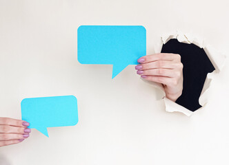 Dialogue icon. Blank speech bubble. Female hands inside breakthrough paper hole showing blue...