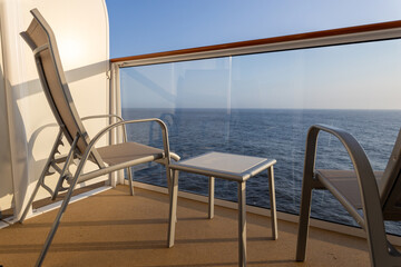 Cruise ship balcony with two chairs and table.