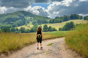 Junge Frau auf einer Wanderung im idyllischen Hügelland des Odenwaldes, Hessen, Deutschland,...