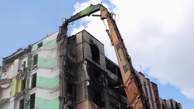 Demolition of a high-rise building. The collapse of a residential building. Construction work on the demolition of multi-storey apartments. Excavator with hydraulic crusher.