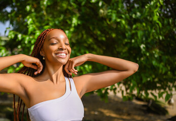Fototapeta premium Outdoor portrait of natural Beautiful young African American woman long red braids hair style and perfect white teeth smile, posing in swimsuit at sunny summer day with green foliage beach background