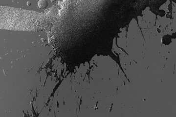 Abstract Black grain spray ink blot drops gray background.