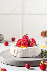 Camembert cheese with fresh berries, honey and thyme on white background. Healthy snack. Vertical orientation