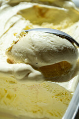 Vanilla ice cream scooped out of a container with a spoon