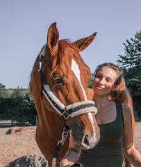 Fototapeta premium Portrait einer jungen blonden Frau, die neben dem Kopf ihres jungen Pferdes mit Fellhalfter steht und es verliebt anschaut