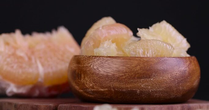 take freshly peeled and divided into pieces pink pomelo on the table, sweet fresh citrus pomelo on the kitchen table