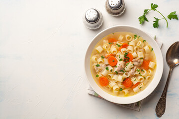 Chicken soup with pasta in plate on concrete background