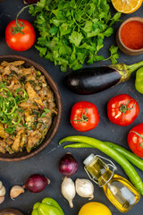 Above view of delicious dinner with eggplant dish fresh vegetables green bundle pepper on black table