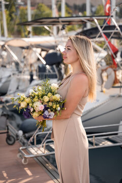 A beautiful fashion caucasian woman with flowers on luxury yachts background in marina