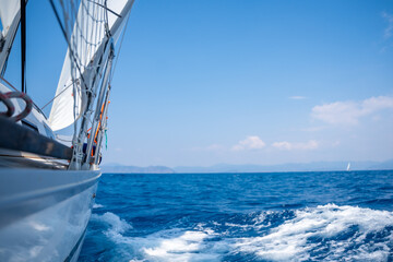 Yacht sailing in an open sea. Close-up view of side of the boat. Clear sky after the rain, waves and water splashes