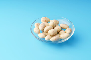 Roasted peanuts in creamy yogurt with coconut flakes on a blue background