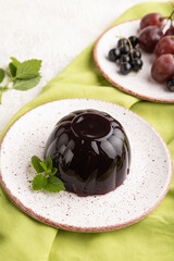 Black currant and grapes jelly on gray concrete. side view, close up.