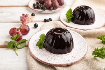Black currant and grapes jelly on white wooden. side view.
