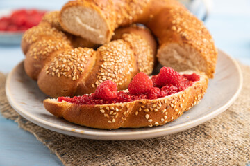 Homemade sweet bun with raspberry jam and cup of coffee on a blue wooden. side view, selective focus.
