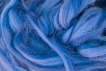 Multicolored blue strings of wool for felting and spinning as a background.
