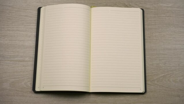 Businessman puts diary on the wooden table opens it in blank page.