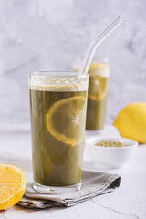 Refreshing matcha tea with lemon in glasses with straws on the table vertical view