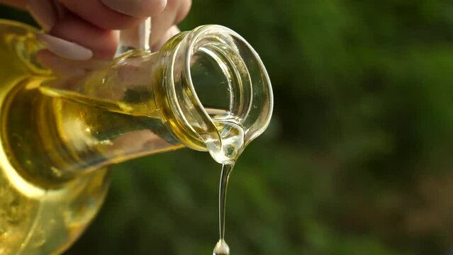 Pouring olive oil from a glass bottle