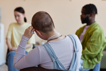Fototapeta premium Rear view of shaved woman sitting with group at psychotherapy session in office