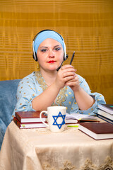 A Jewish woman in a kisui rosh headdress, a Torah teacher in headphones with a microphone, conducts...